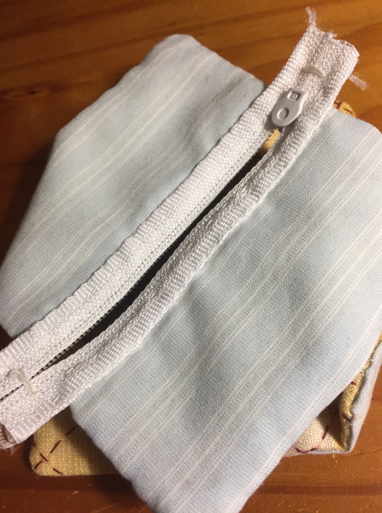 Partly assembled pouch, inside out, showing the stripped light blue lining and the zipper