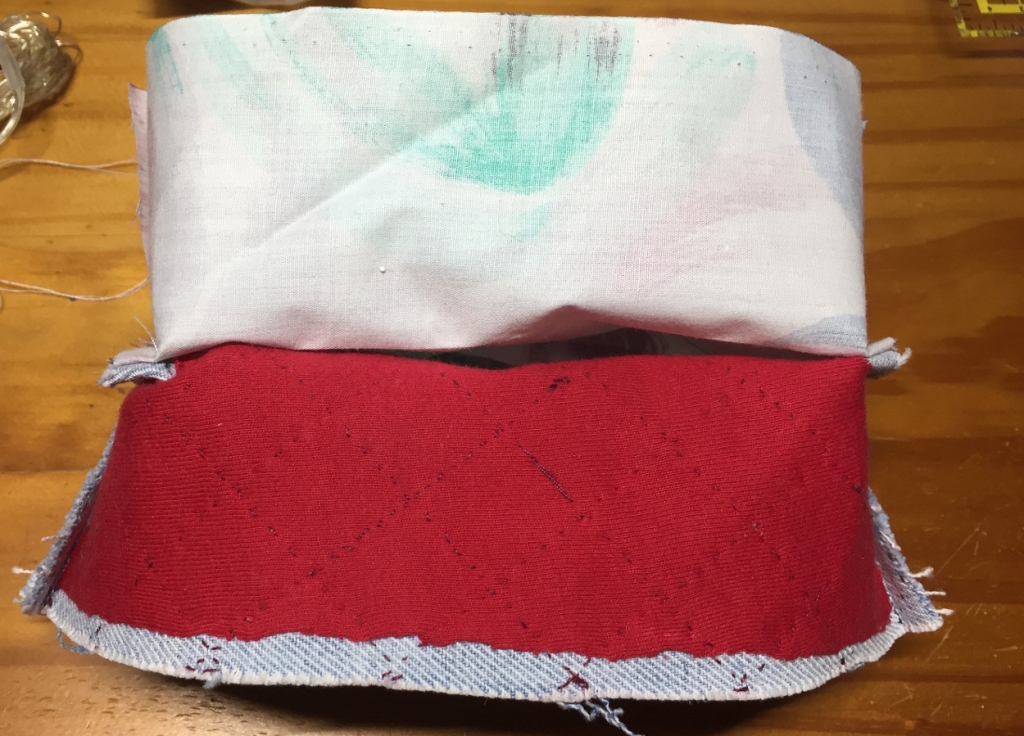 Shell and lining of the square bottom half, both inside out, attached to each other by the bottom side seams. This shows the red t-shirt I used as interface, attached to the denim shell through the quilting stitches.