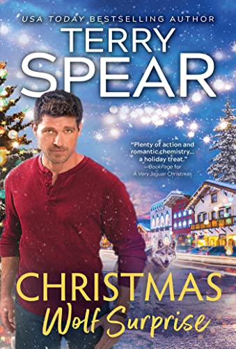 A handsome, fairly muscular white man with dark hair wearing a longsleeve thermal-type of shirt and jeans; in the background, a small town street with Christmas lights, falling  snow and pine trees, and a worlf walking down the street.