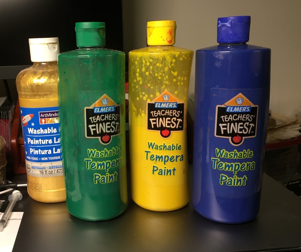 Four large, and quite depleted by now, bottles of washable tempera/acrylic paint. The green bottle has perhaps a quarter left, and the yellow about half. The blue one is opaque, so it's impossible to tell, and the gold one is probably four fifths full.